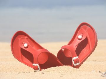 Imagen de unas chanclas en la arena de la playa