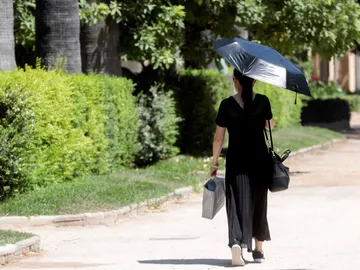 Una mujer se protege con un parasol Una mujer se protege con un parasol