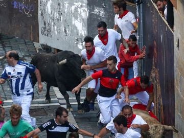 Un toro de Núñez del Cuvillo junto a varios mozos a su paso por la curva de Mercaderes