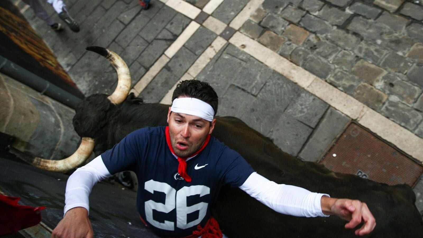 Los dos momentos de mayor peligro del séptimo encierro de San Fermín: una cornada y un fuerte golpe contra la valla