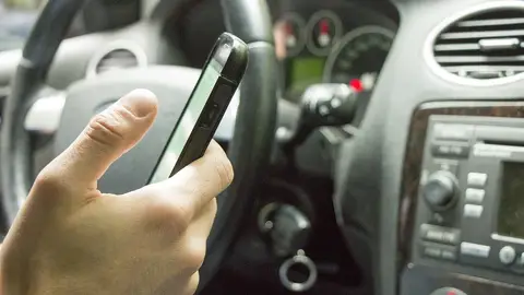 Imagen de archivo de un conductor usando el móvil al volante Imagen de archivo de un conductor usando el móvil al volante