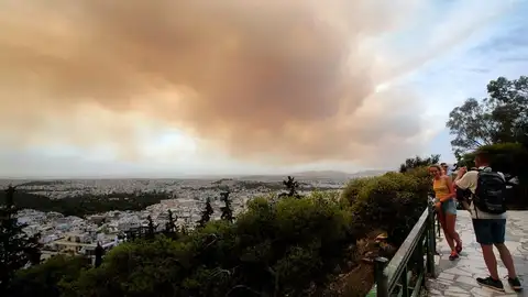 Unos turistas fotografían las nubes densas de humo que se expanden en el cielo debido un incendio en las montañas de Gerania, a 54 km de Atenas Unos turistas fotografían las nubes densas de humo que se expanden en el cielo debido un incendio en las montañas de Gerania, a 54 km de Atenas
