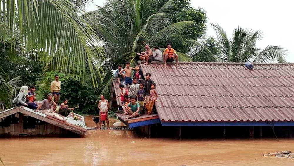 Un grupo de personas aguarda en lo alto de un tejado en una zona inundada tras el derrumbe de una presa hidroeléctrica en un pueblo cercano a la provincia de Attapeu, en Laos.