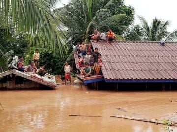 Un grupo de personas aguarda en lo alto de un tejado en una zona inundada tras el derrumbe de una presa hidroeléctrica en un pueblo cercano a la provincia de Attapeu, en Laos.