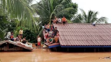 Un grupo de personas aguarda en lo alto de un tejado en una zona inundada tras el derrumbe de una presa hidroeléctrica en un pueblo cercano a la provincia de Attapeu, en Laos.