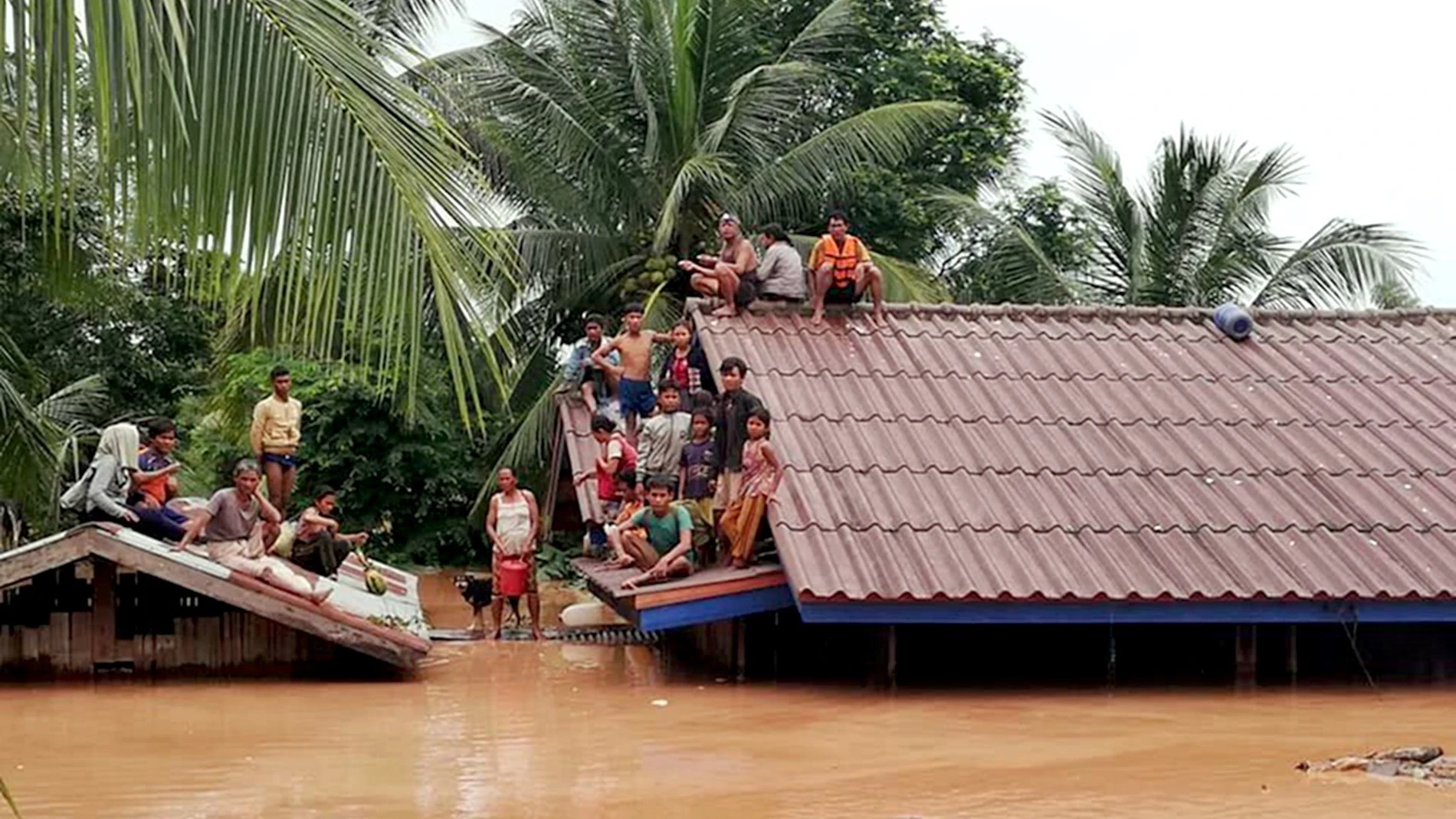 Un grupo de personas aguarda en lo alto de un tejado en una zona inundada tras el derrumbe de una presa hidroeléctrica en un pueblo cercano a la provincia de Attapeu, en Laos. Un grupo de personas aguarda en lo alto de un tejado en una zona inundada tras el derrumbe de una presa hidroeléctrica en un pueblo cercano a la provincia de Attapeu, en Laos.
