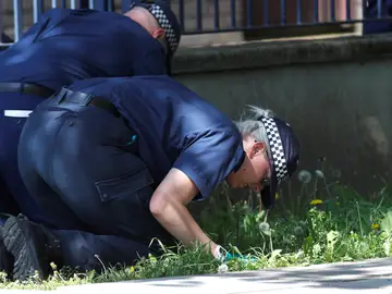 Policías británicos buscando pruebas sobre la escena de un crimen Policías británicos buscando pruebas sobre la escena de un crimen