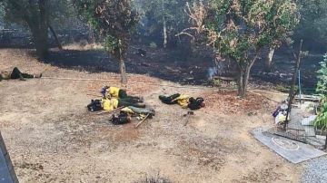 Bomberos de California descansando en el patio trasero de una casa después de salvarla de las llamas