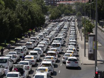 Un grupo de taxis permanecen concentrados a su paso por el ministerio de Fomento