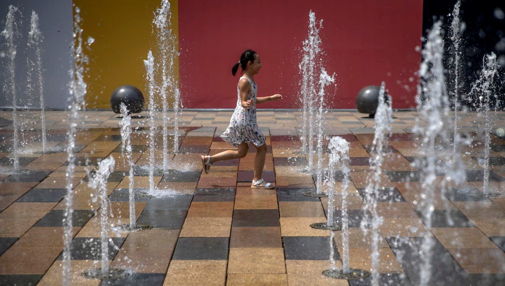 A child plays in a fountain in the Sanlitun area of Beijing, China