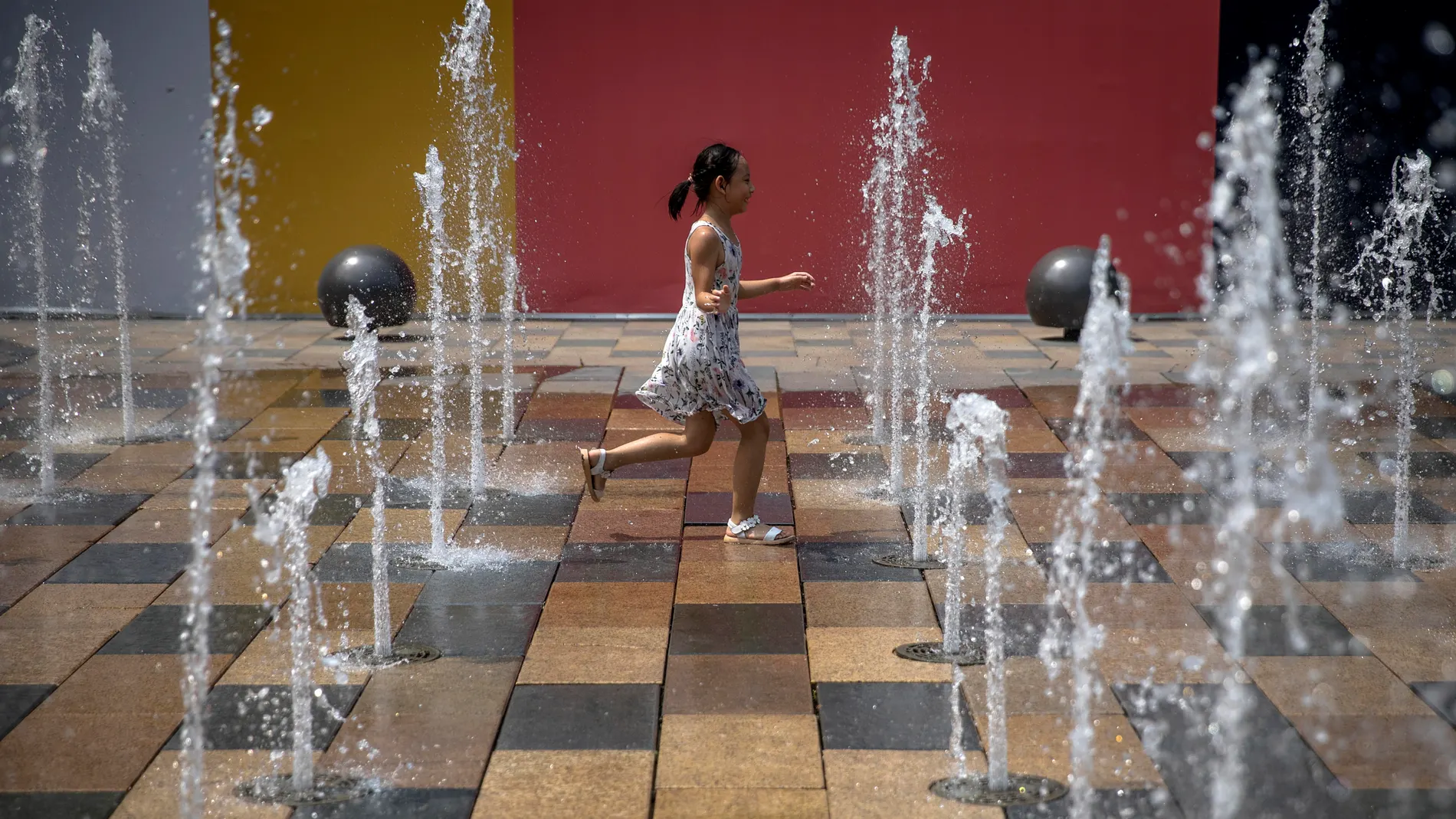 A child plays in a fountain in the Sanlitun area of Beijing, China A child plays in a fountain in the Sanlitun area of Beijing, China