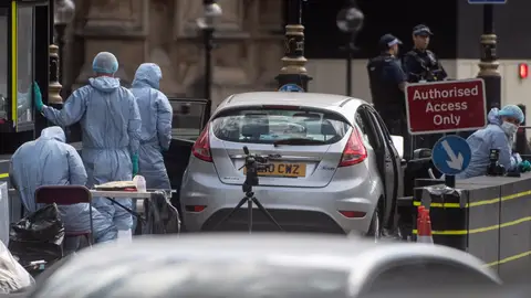 Oficiales forenses examinan el coche que chocó contra las barreras del Parlamento británico Oficiales forenses examinan el coche que chocó contra las barreras del Parlamento británico