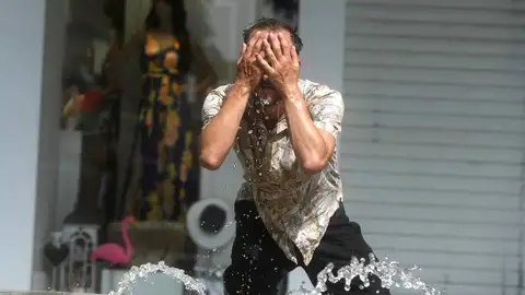 Un hombre intenta refrescarse en una fuente Un hombre intenta refrescarse en una fuente