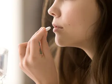 Imagen de una mujer tomando una pastilla. Imagen de una mujer tomando una pastilla.