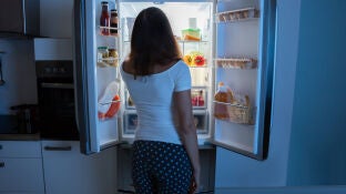 Una mujer frente a una nevera abierta