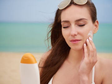 Mujer poniendo crema solar en la cara
