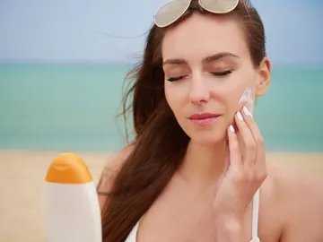 Mujer poniendo crema solar en la cara Mujer poniendo crema solar en la cara