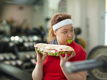 Una chica come un bocadillo enorme en el gimnasio