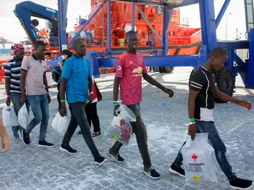 Varios inmigrantes salen de la embarcacíon para subir a un autobús que los llevará a San Roque Varios inmigrantes salen de la embarcacíon para subir a un autobús que los llevará a San Roque