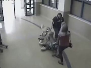 Una profesora y una enfermera de una escuela arrastran por el pasillo a un niño autista y a su perro guía