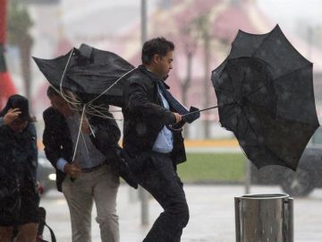 Imagen de archivo: Varias personas sujetan sus paraguas por el fuerte viento.