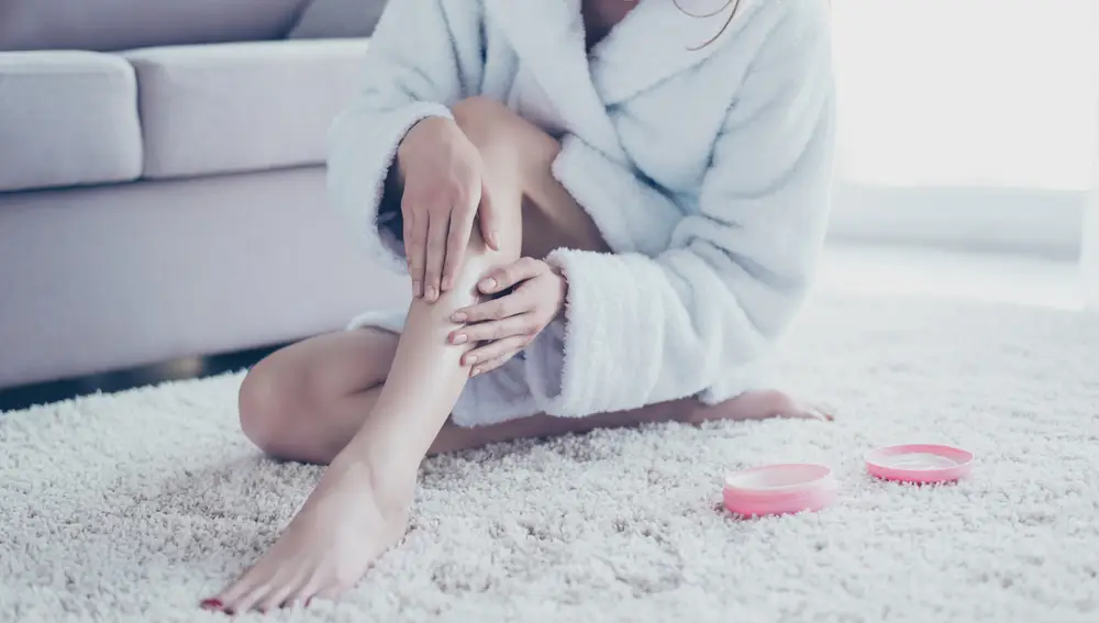 Mujer aplicando crema en las piernas