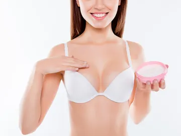 Mujer poniéndose crema en el pecho Mujer poniéndose crema en el pecho