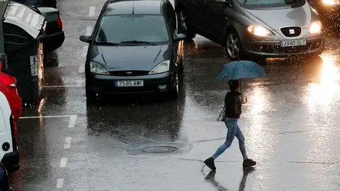 Media España en alerta naranja y amarilla por viento y lluvia Imagen de una persona que se protege con un paraguas de la lluvia