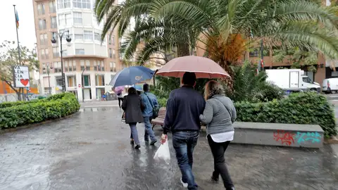 Varias personas pasean protegidas con paraguas Varias personas pasean protegidas con paraguas
