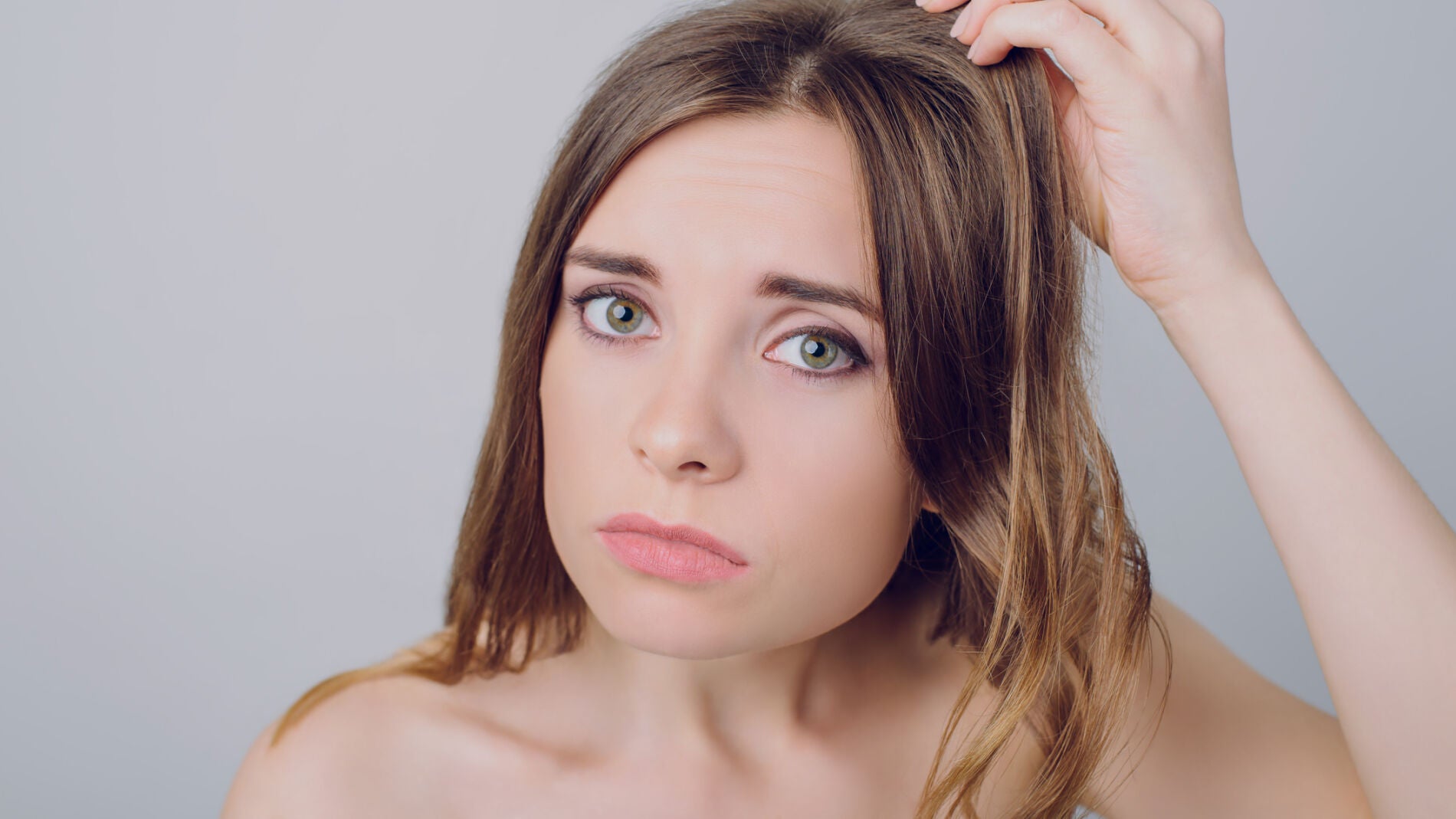 Mujer mira su pelo preocupada