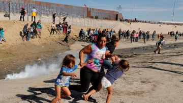 Mujer hondureña que forma parte de la caravana hacia EE.UU. huye con sus hijas de los gases lacrimógenos