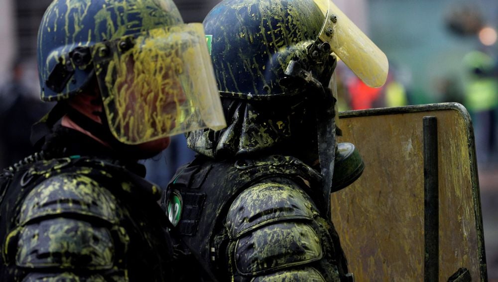 Agentes antidisturbios con los cascos manchados de pintura amarilla