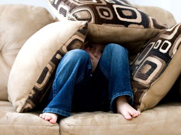 ni&ntilde;o en un sof&aacute; con pies descalzos