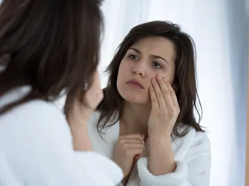 Mujer se mira los ojos frente al espejo Mujer se mira los ojos frente al espejo