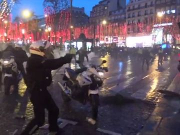 REEMPLAZO Un policía francés apunta con su arma a los 'chalecos amarillos' tras lanzar estos objetos contra los agentes y derribar la moto de uno de ellos