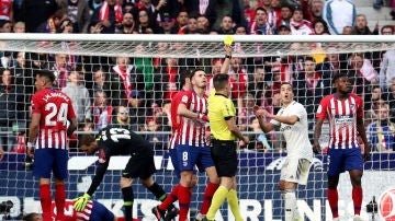 Estrada Fernández muestra una tarjeta amarilla durante el Atlético-Real Madrid