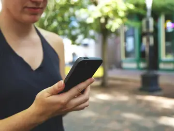 Una usuaria con su teléfono móvil Una usuaria con su teléfono móvil