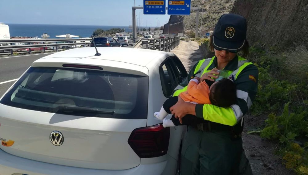 Agente de la Guardia Civil dando de comer a un bebé en la carretera