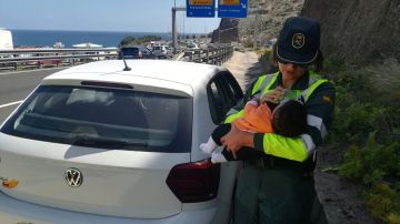 Agente de la Guardia Civil dando de comer a un bebé en la carretera