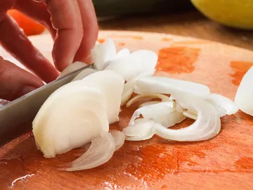 Cortar cebolla sobre una tabla Cortar cebolla sobre una tabla