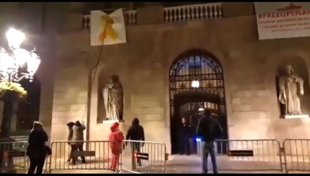 Un grupo de personas retiran el lazo amarillo del Ayuntamiento de Barcelona