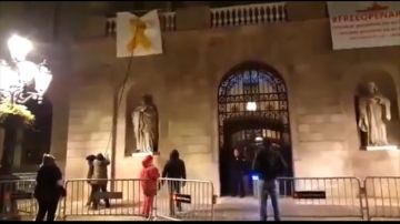 Un grupo de personas retiran el lazo amarillo del Ayuntamiento de Barcelona