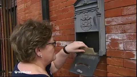 Una vecina abriendo el buzón de su casa Una vecina abriendo el buzón de su casa
