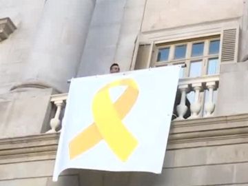 Antena 3 Noticias 1 (14-03-19) Un grupo de personas descuelga una pancarta con un lazo amarillo del Ayuntamiento de Barcelona y operarios la vuelven a colocar