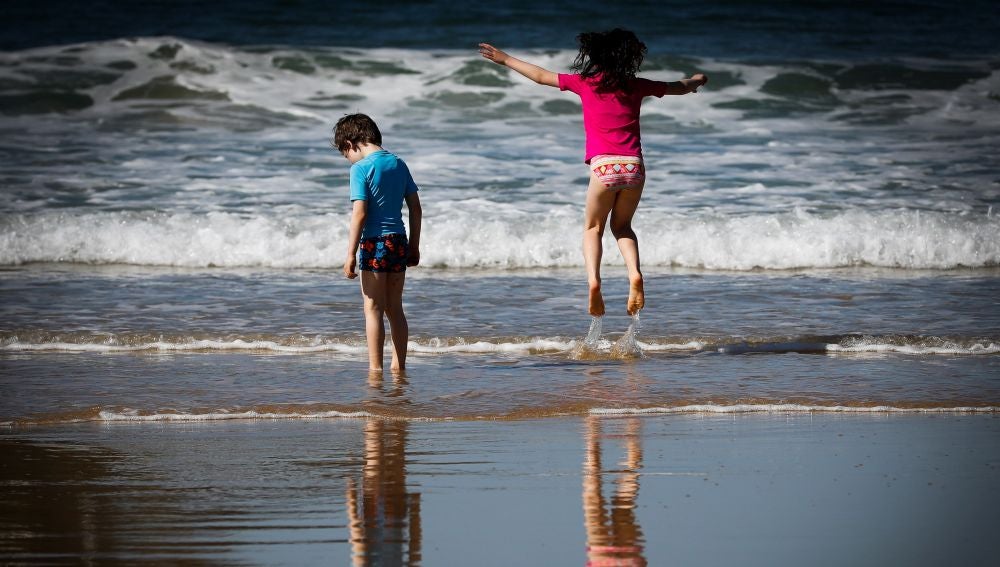 Dos niños disfrutan de otro día soleado en la orilla de la playa