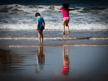 Dos niños disfrutan de otro día soleado en la orilla de la playa Dos niños disfrutan de otro día soleado en la orilla de la playa