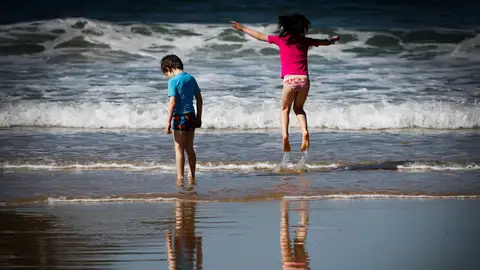 Dos niños disfrutan de otro día soleado en la orilla de la playa Dos niños disfrutan de otro día soleado en la orilla de la playa