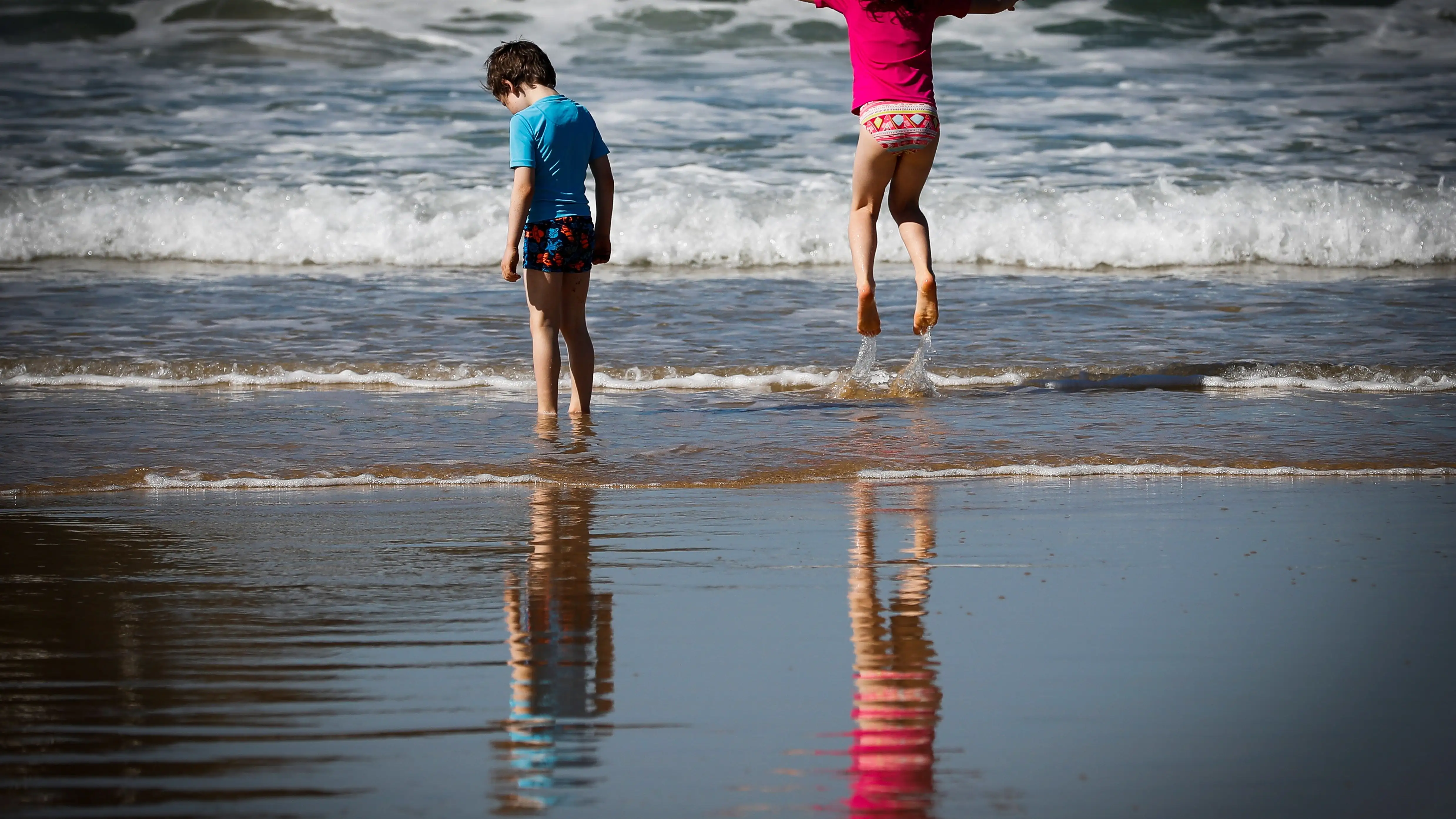 Dos niños disfrutan de otro día soleado en la orilla de la playa Dos niños disfrutan de otro día soleado en la orilla de la playa