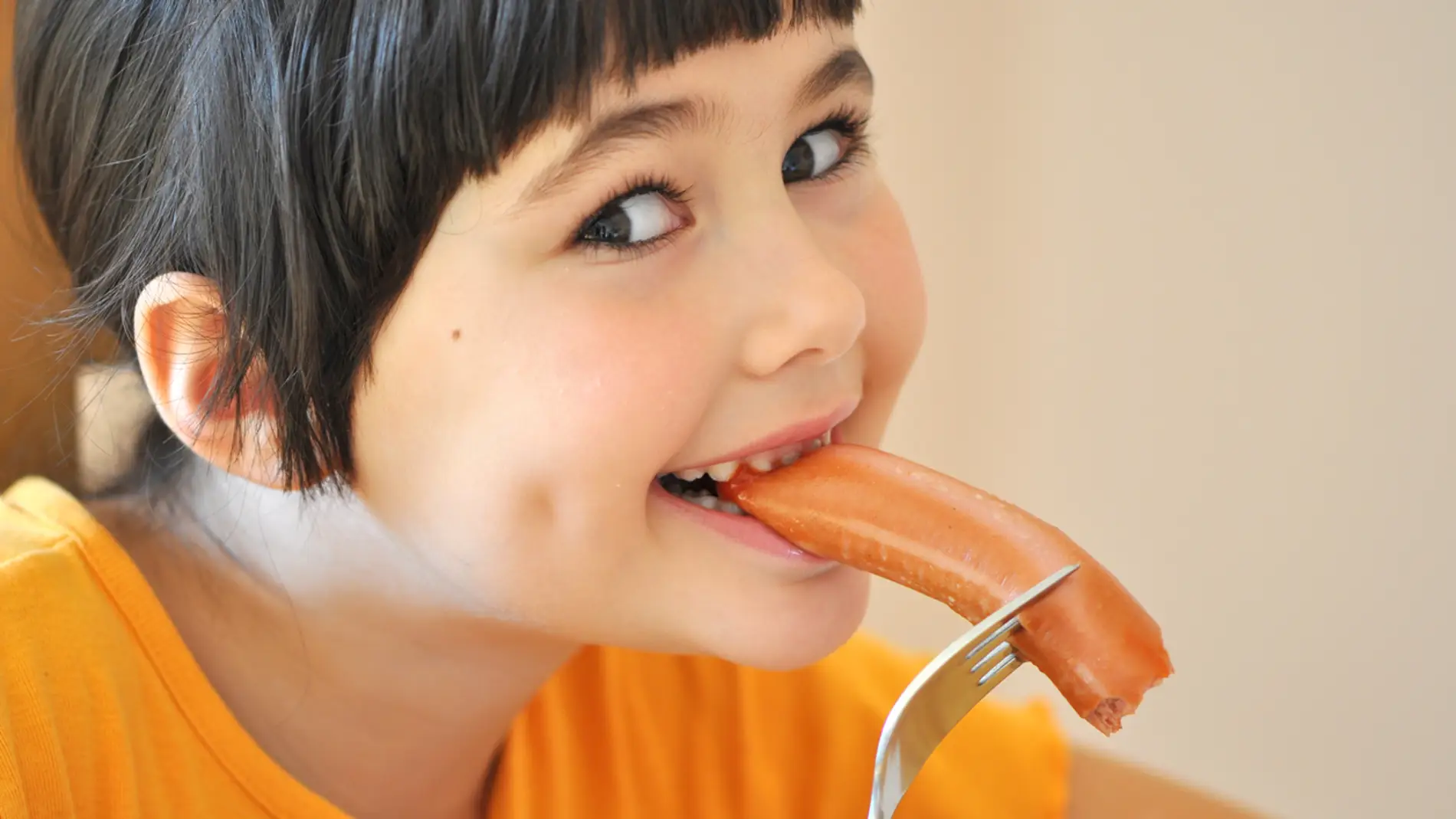 Niña comiendo salchicha