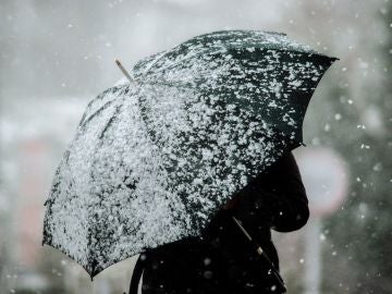 Una mujer protegiéndose de la nieve con un paraguas